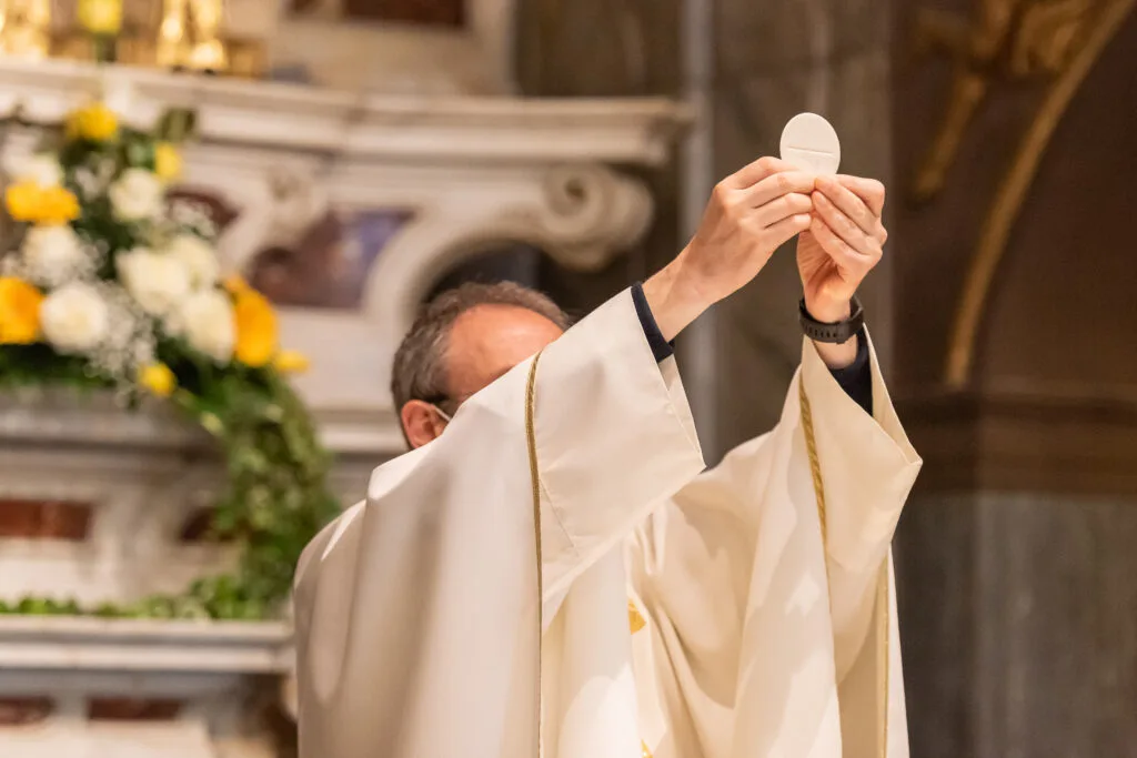 Sacerdote consagrando a hóstia, momento central celebrado em Corpus Christi